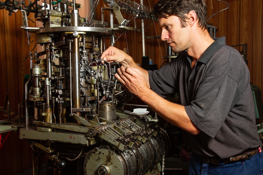 Man maintaining wool knitting machine.