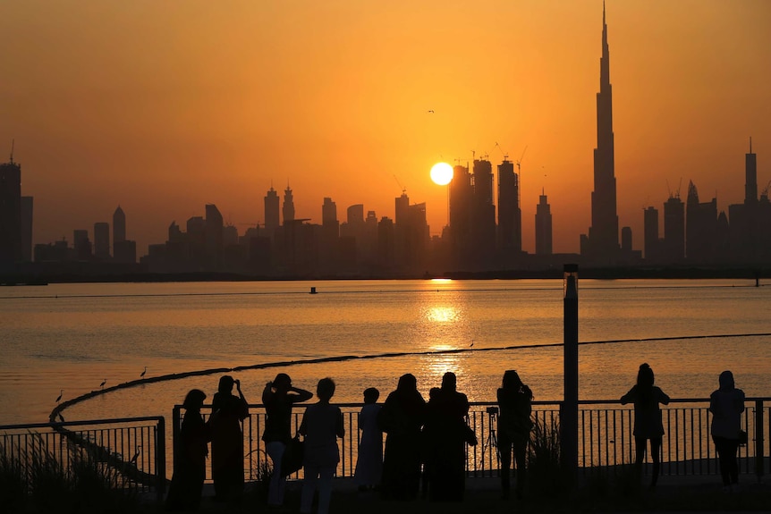 People watch the sunset over the Dubai skyline, with Burj Khalifa at right.
