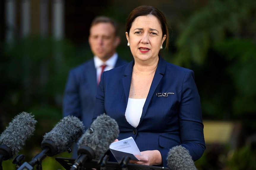 Queensland Premier Annastacia Palaszczuk speaking to reporters, with Health Minister Steven Miles in the background