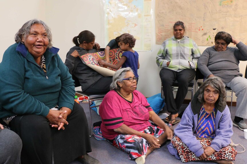 Members of the Tangentyere Women's Safety Group sit on chairs and on the floor during a meeting.