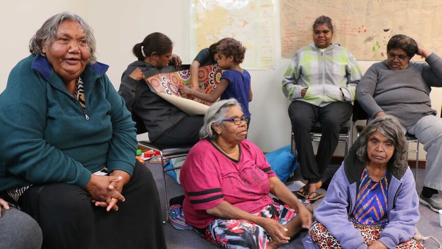 Members of the Tangentyere Women's Safety Group sit on chairs and on the floor during a meeting.