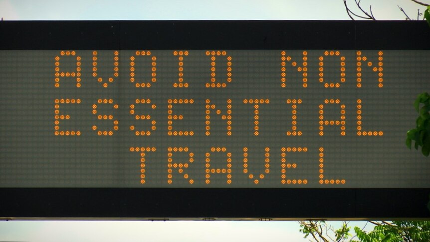 A black road sign with orange neon writing 'Avoid non essential travel'