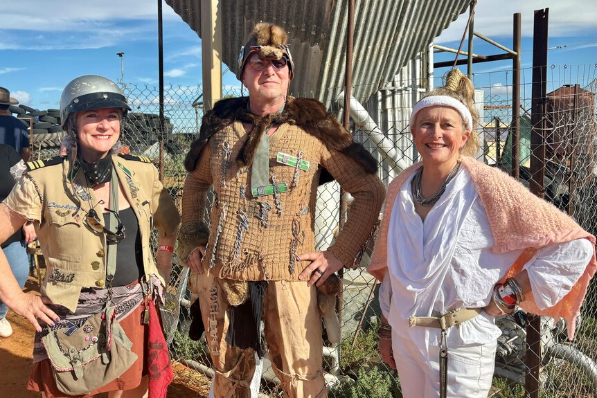Three people stand with their hands on hips wearing post apocalyptic outfits