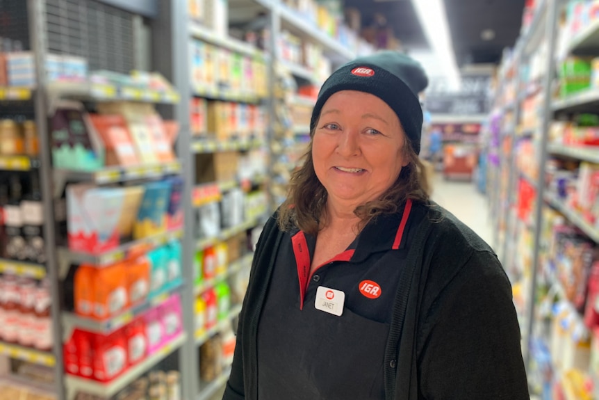 woman wearing a black beanie and black t-shirt stands in a supermarket