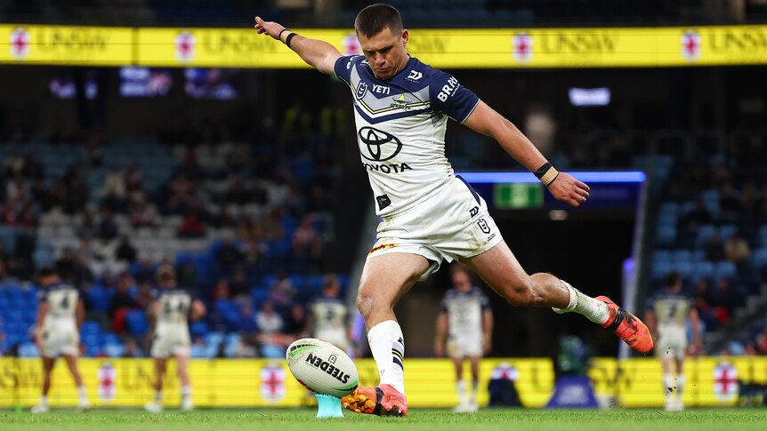 A Cowboys NRL player takes a place kick from the tee against the Roosters.