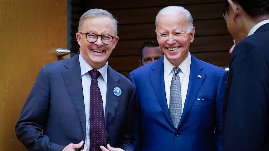 Joe Biden and Anthony Albanese laughing while walking through a door