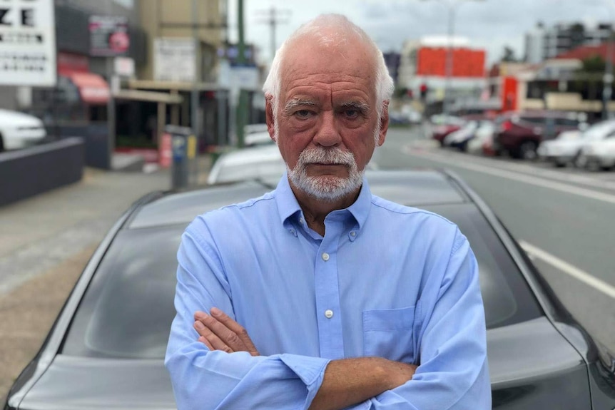 Glen Crawford sitting on the bonnet of a parked car.