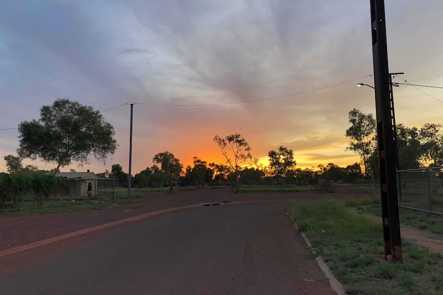 The sun sets behind trees at Tennant Creek