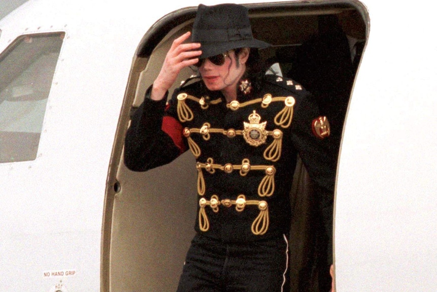 Michael Jackson holds his hat as he climbs from a private jet in 1997.