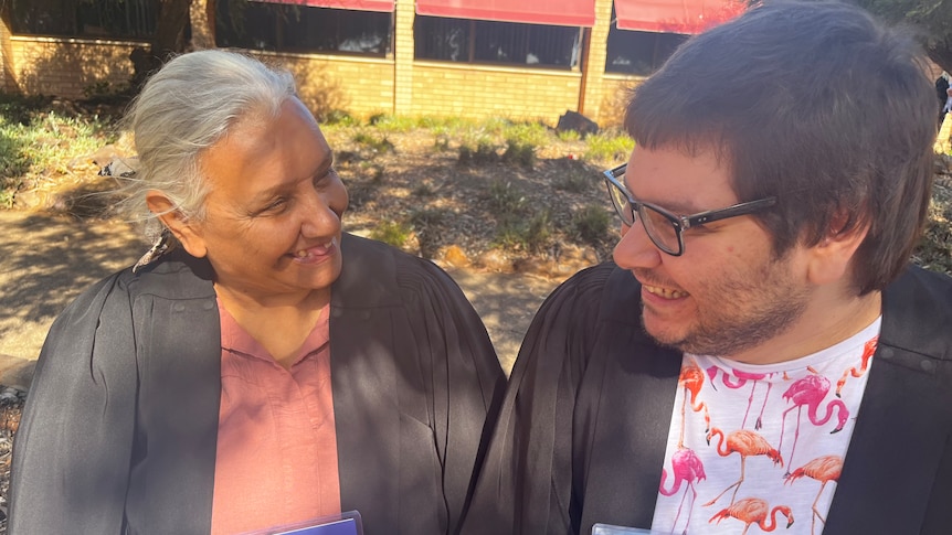 A mother and son laughing at their joint graduation. 