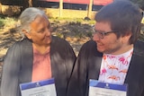 A mother and son laughing at their joint graduation. 