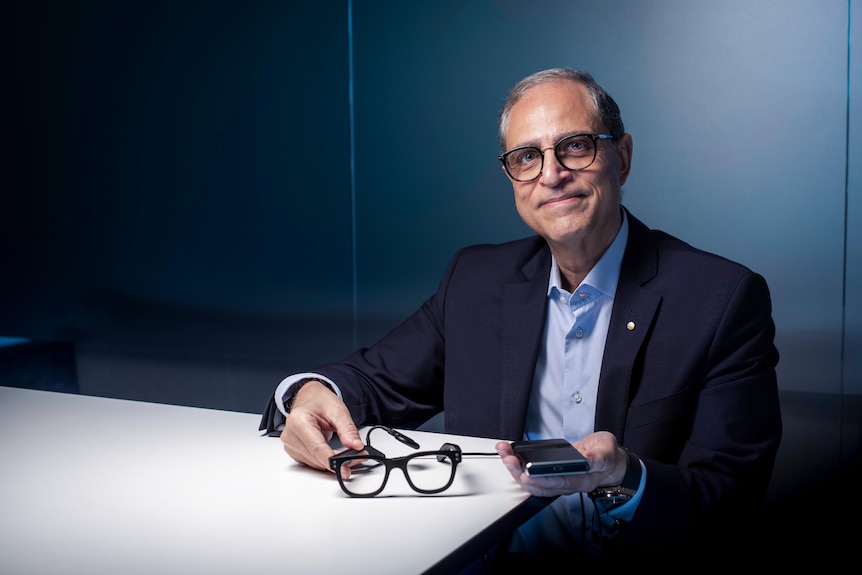 Man holding a pair of glasses and a hard drive. 