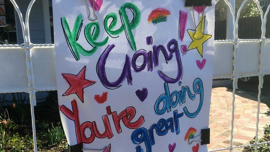 A white hand-drawn sign in colourful print which says keep going, you're doing great.