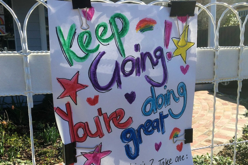 A white hand-drawn sign in colourful print which says keep going, you're doing great.