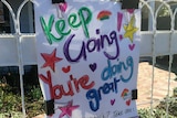 A white hand-drawn sign in colourful print which says keep going, you're doing great.