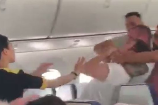 man on plane being held in chokehold as other passengers look on