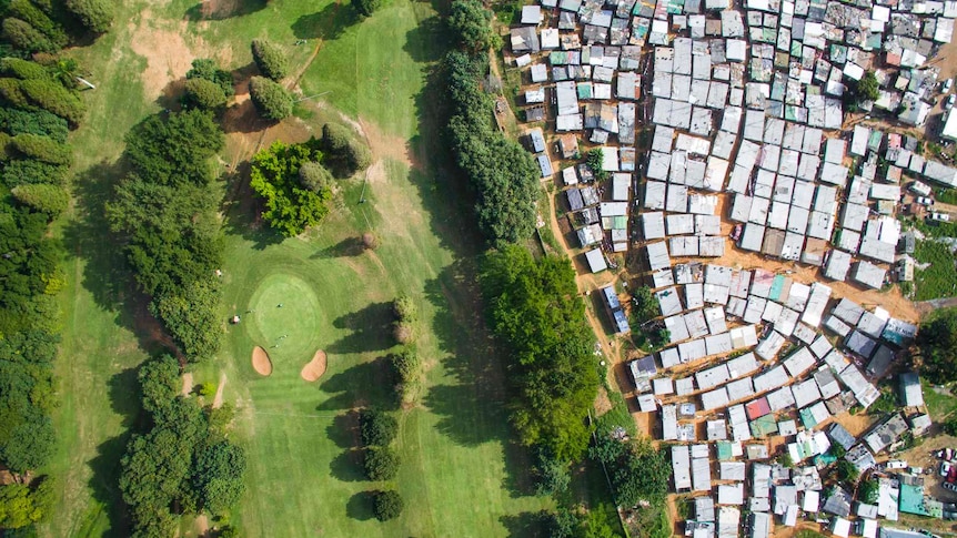 An aerial photo showing golf course and slums side by side