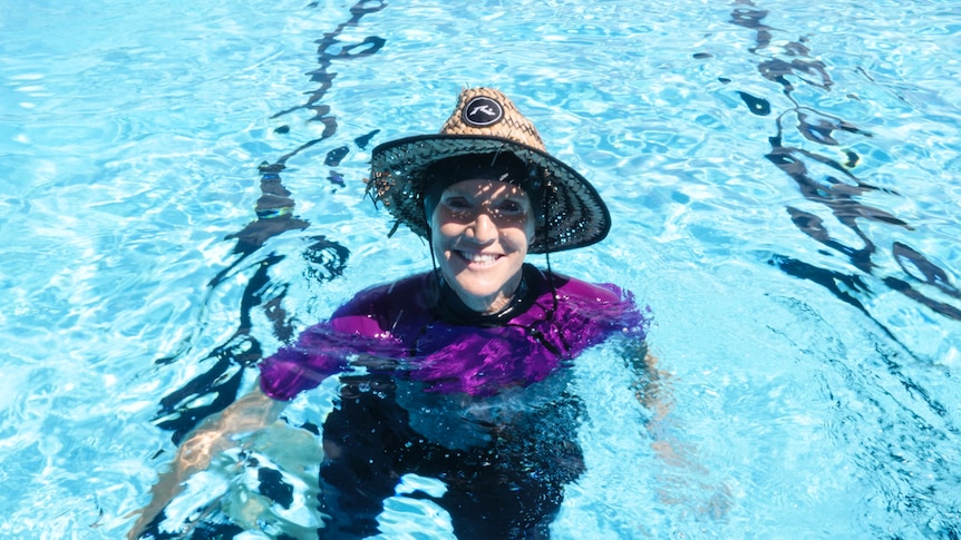 A teacher smiles from the pool water.
