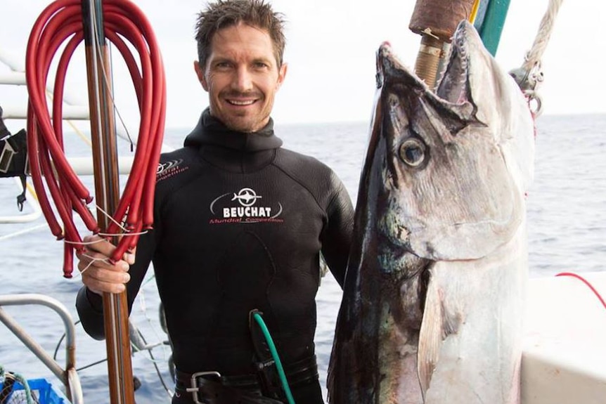 Ben Leahy standing on a boat displaying a large fish he caught, date and location unknown