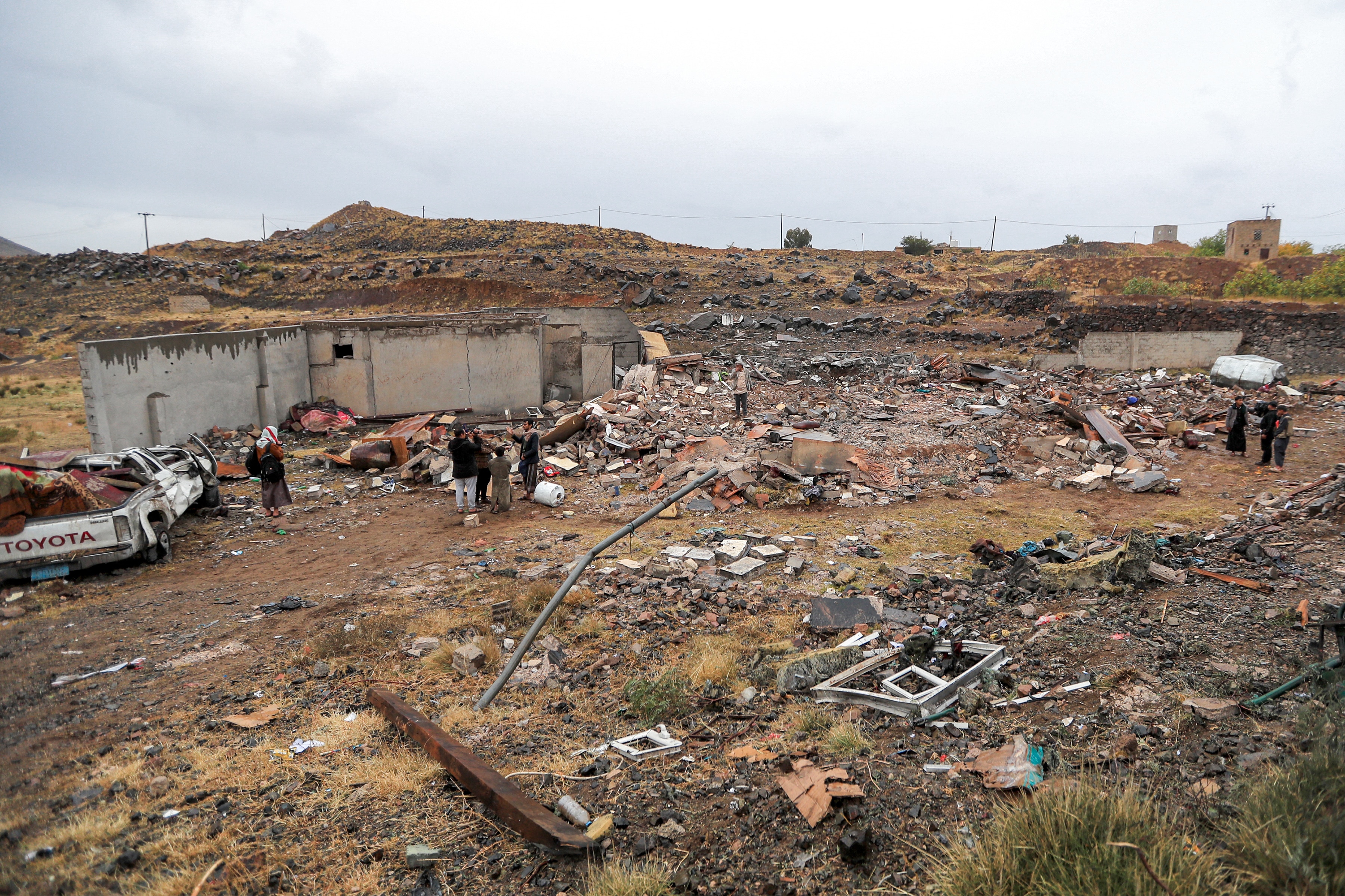 People stand among the rubble of a destroyed building.