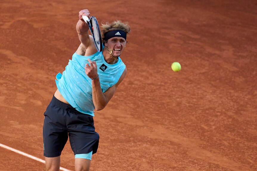 A German tennis star grimaces as he hits the ball back to his opponent in a clay-court tournament.