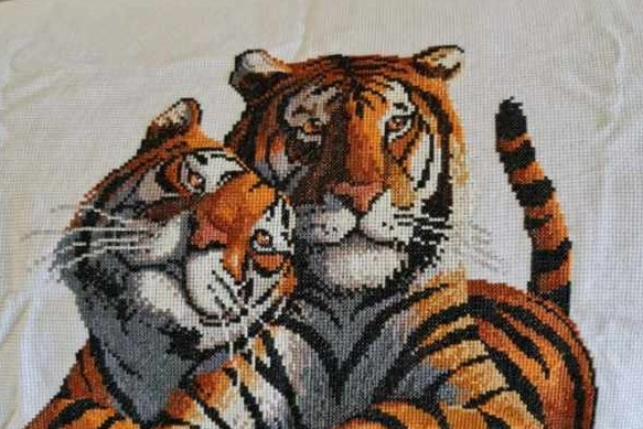 a cross-stitch of two tigers