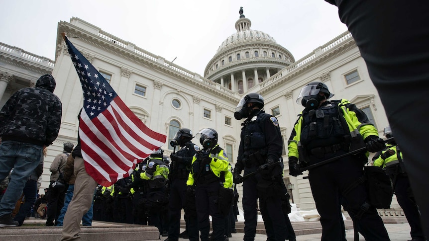 Police line up in front of the Capitol Building facing off against protesters