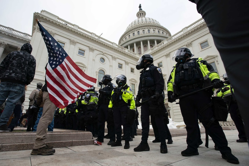 Police line up in front of the Capitol Building facing off against protesters