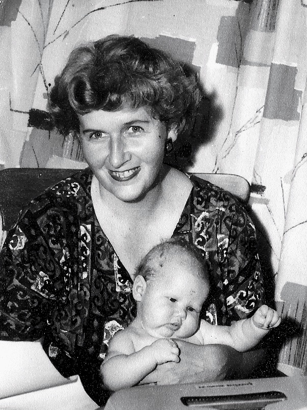 A black and white photo of a woman with a baby at a typewriter.