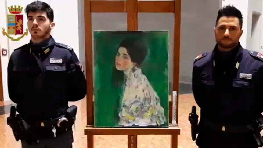 Two police officers stand either side of the painting