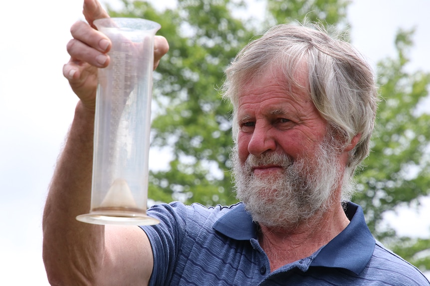 Cranbrook farmer David Amos, looks at rain he has collected on his Tasmanian property.