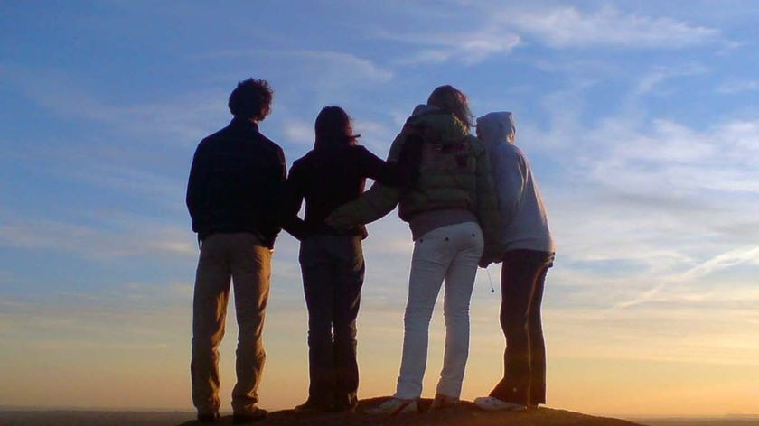 Four youths stand on a boulder