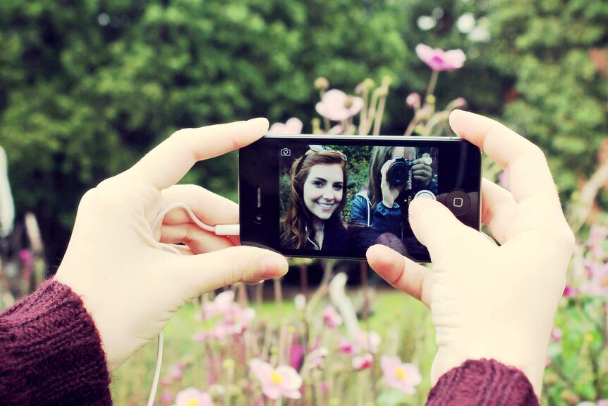 Two girlfriends take a selfie using a smartphone in the garden