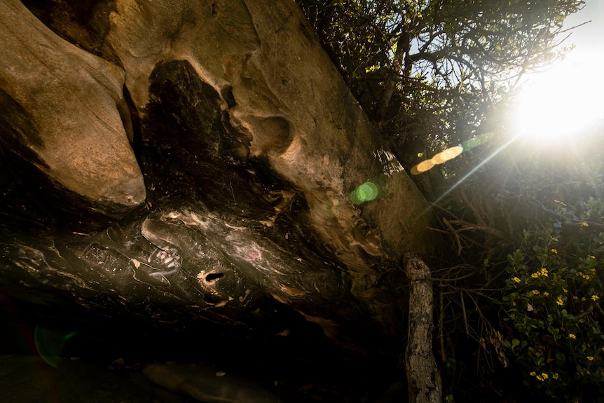 A handprint and some other drawings stand out on a darkened cave's roof.