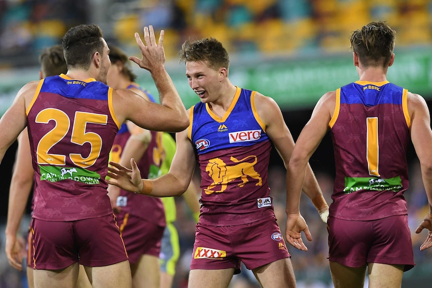 Alex Witherden of the Lions (C) celebrates his first goal against Carlton at the Gabba.