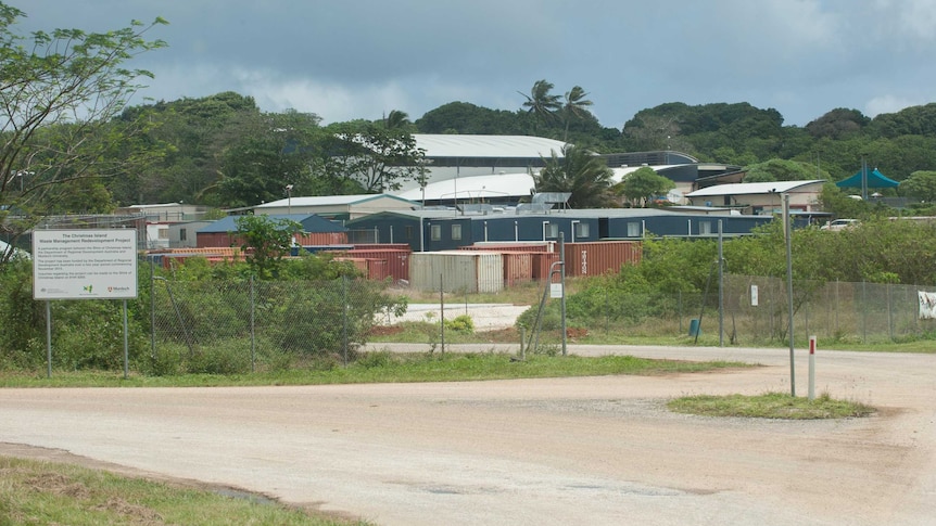 Tin rooves of buildings in the background, with a gravel parking lot in the foreground.