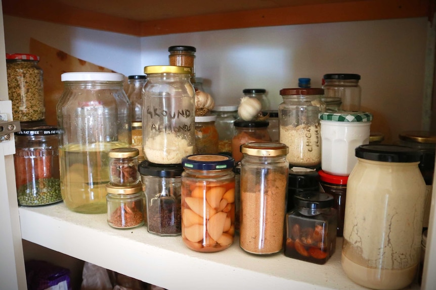 A number of household items in jars in a pantry