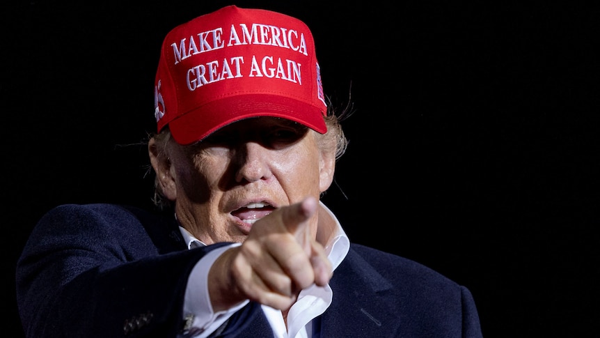Donald Trump points his finger while wearing a make america great again cap. it looks like he's yelling