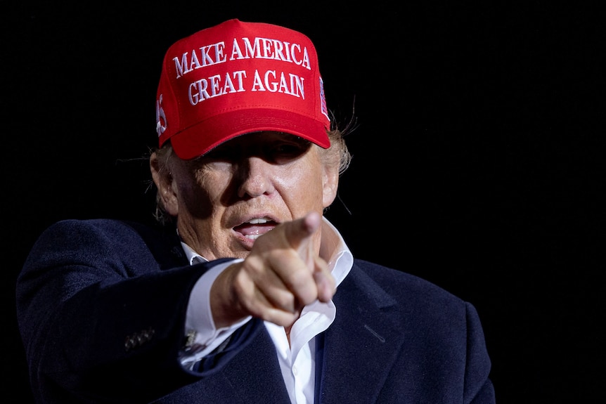 Donald Trump points his finger while wearing a make america great again cap. it looks like he's yelling