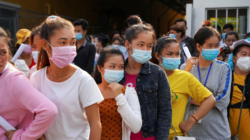 A line of women in Cambodia, all wearing face masks
