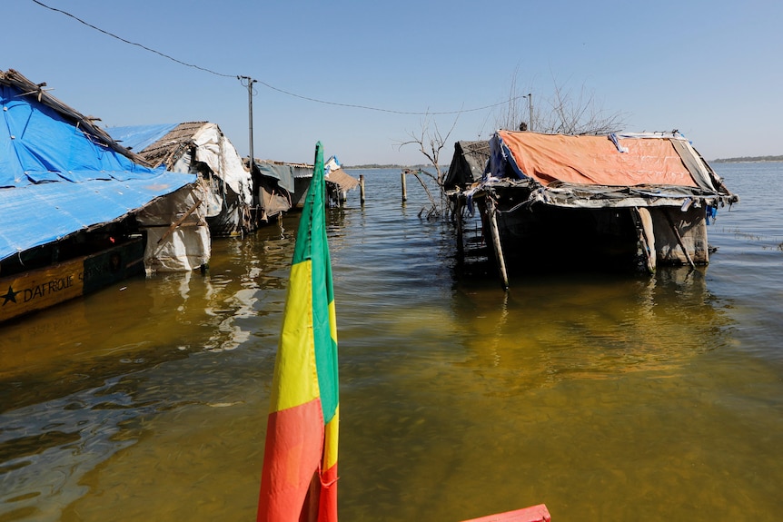 Structures submerged in water with a red, yellow and green flag in front. 