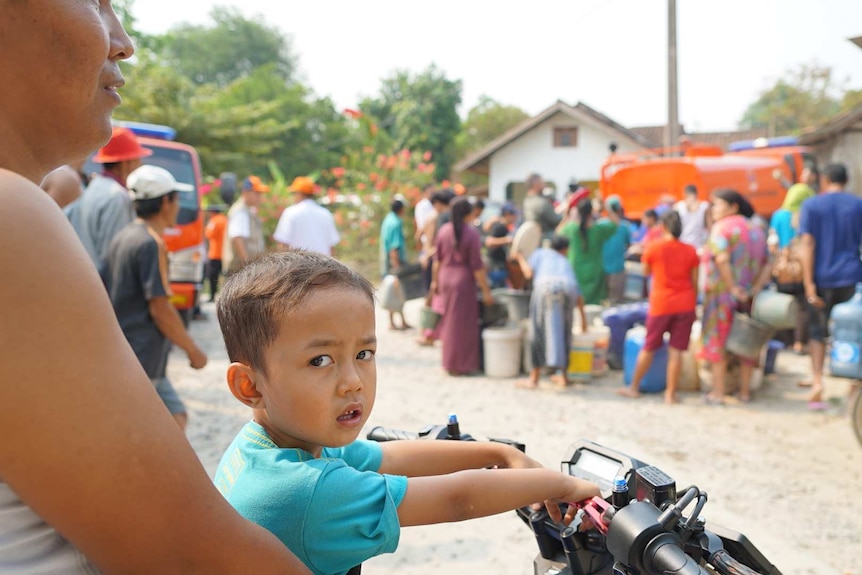 A child sits on the front of a scooter