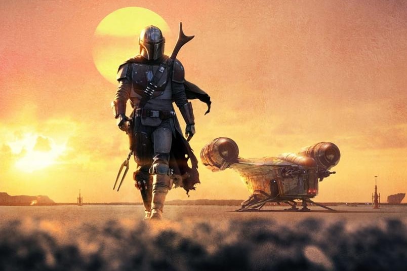 The Mandalorian walks on dirt with a sun in the background.