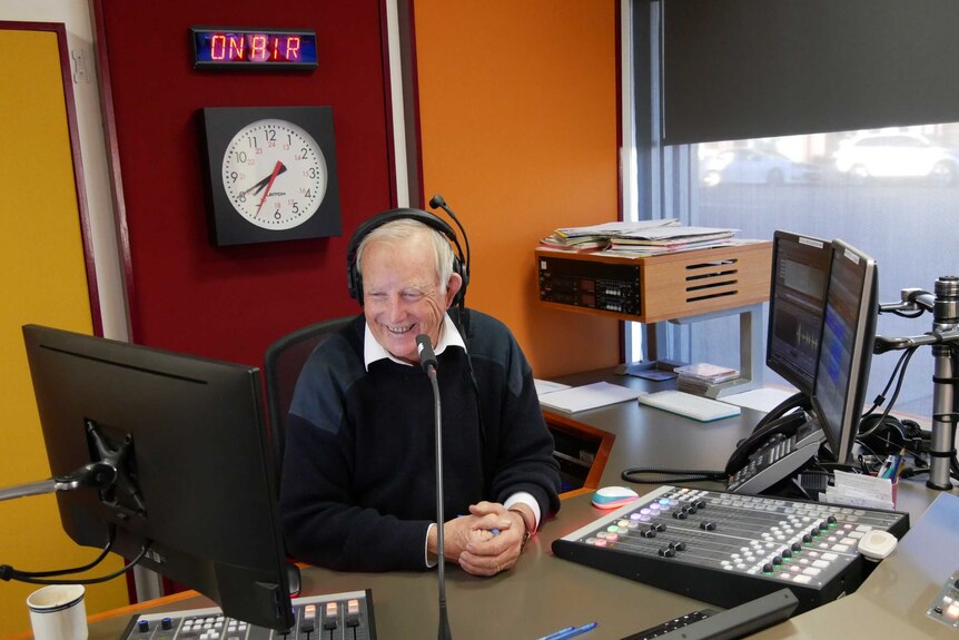 Wide shot of Mike in studio talking into microphone.