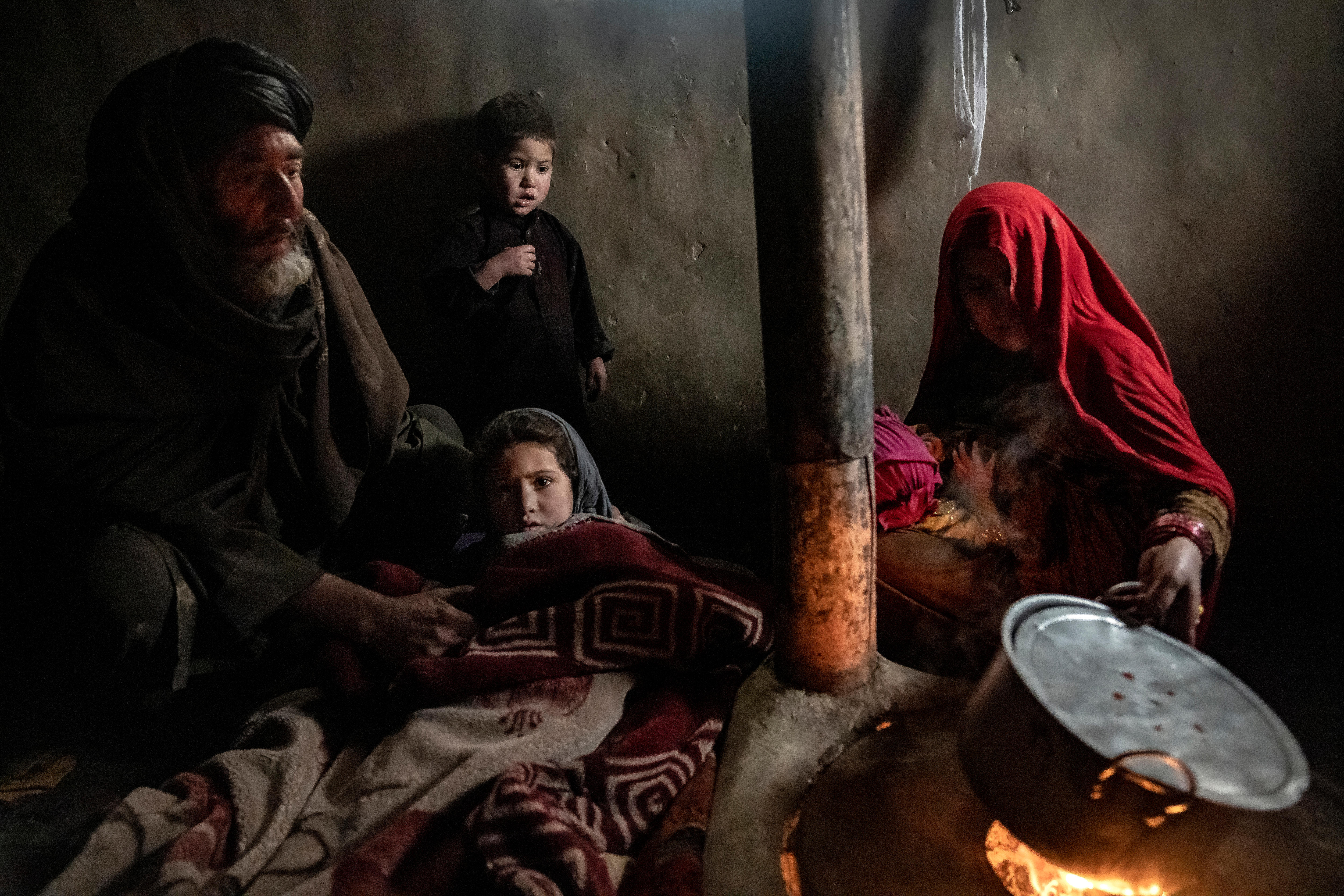 a mother and father cradle a young girl in a blanket by a fire
