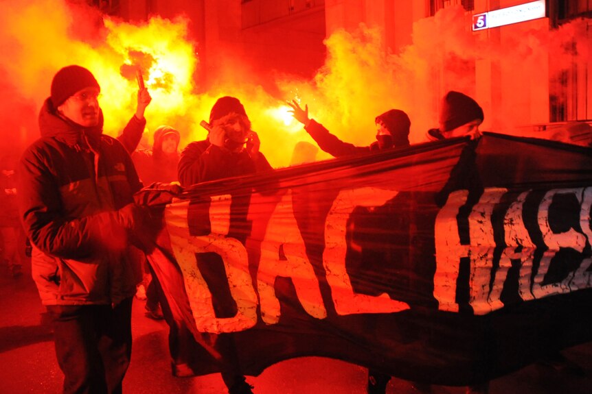 Anarchists burn flares, shout and carry a banner in central Moscow, late on December 4, 2011