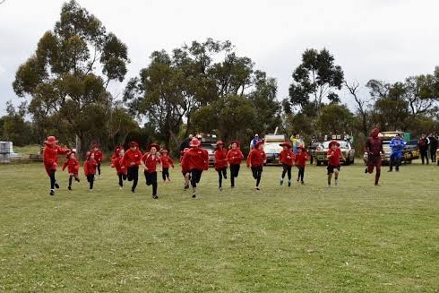 kids running on a field wearing school sports uniforms.