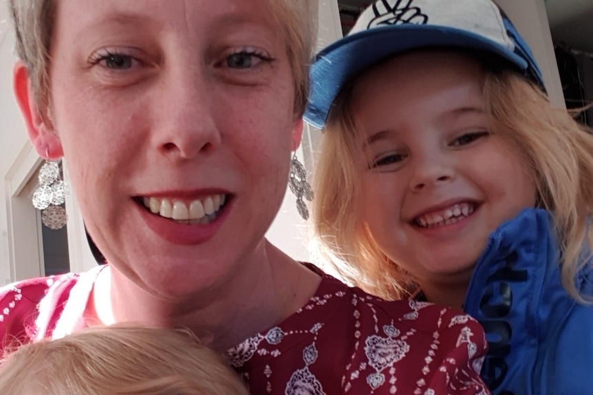 A woman and two children smile in a selfie