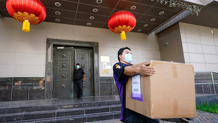 A FedEx employee removes a box from the Chinese Consulate as lanterns hang by the door.