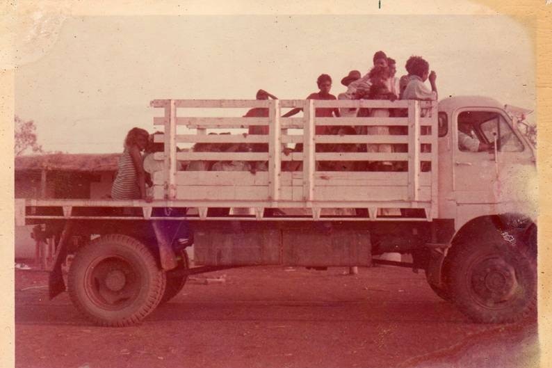 Kids in the back of an open back truck.